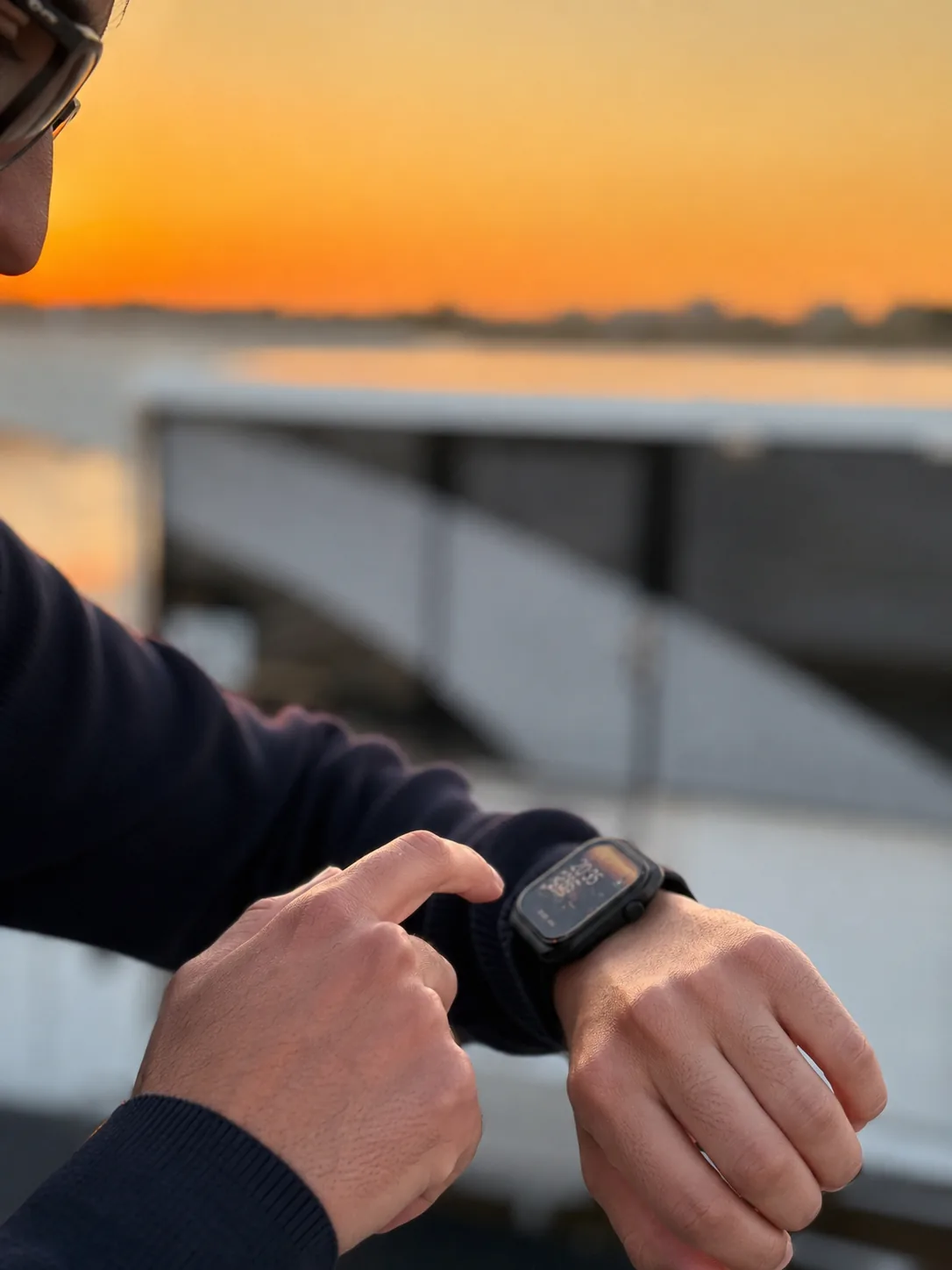 Original close-up of a man checking his black M2 Smartwatch by the waterfront